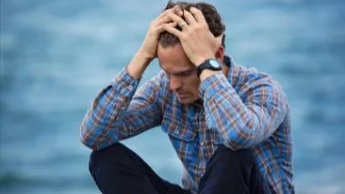 Hombre sentado con las manos en la cabeza, tema como dejar de preocuparme