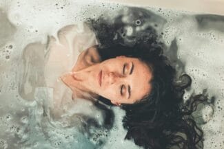 ¡Entendido! Aquí tienes las propuestas de Texto Alternativo y Leyenda para tu imagen, optimizadas para el contexto de tu artículo sobre los síntomas del despertar espiritual: Texto Alternativo (Alt Text): Mujer meditando en una bañera, con los ojos cerrados, en un estado de calma y profunda conexión interior, simbolizando el proceso de reseteo biológico y la adaptación a nuevas frecuencias energéticas durante el despertar espiritual.
